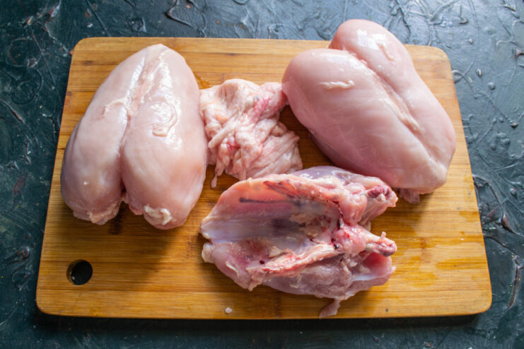 Preparing the Chicken Fillet for the Omelette Raw chicken breasts on a cutting board being prepared for mincing.