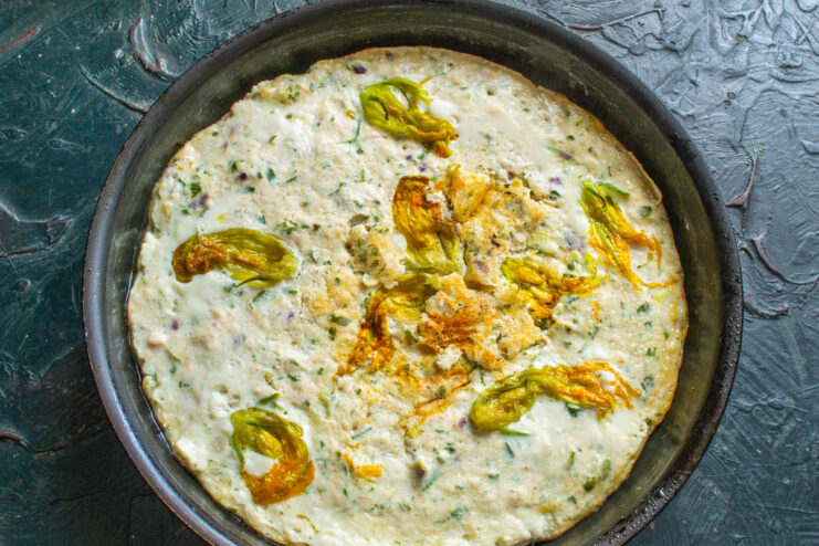 Baking the Arabic-Style Omelette to Perfection The finished Arabic-style omelette, golden brown, baked in a skillet and topped with zucchini flowers.
