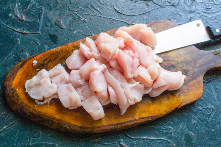Dicing Chicken Fillet for a Perfect Minced Texture Chicken fillet being diced into small cubes on a cutting board.
