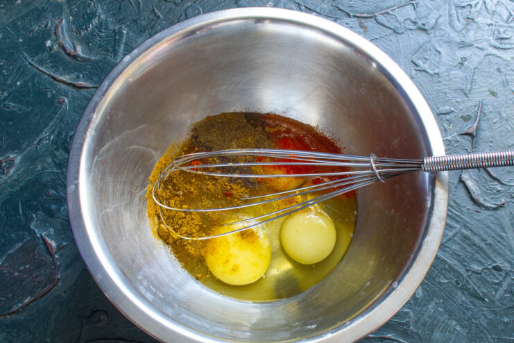 Starting the Omelette Base with Fresh Eggs Four large eggs cracked into a white mixing bowl.