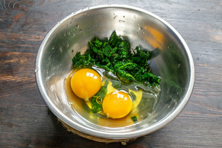 Preparing the Egg Mixture for the Omelet Two chicken eggs cracked into a white bowl.