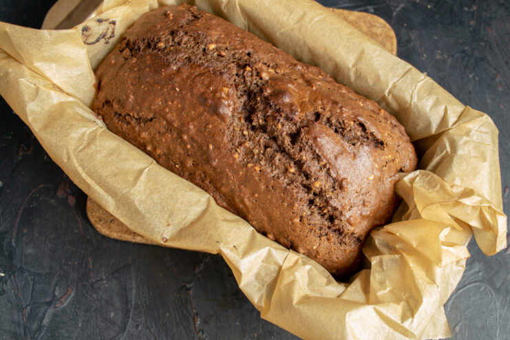 Baking the nut cake until a skewer comes out clean. The loaf pan with cake batter going into a preheated oven.