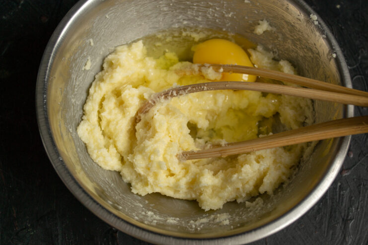 Adding eggs to the creamed butter and sugar mixture. Adding eggs one by one into the bowl with the butter and sugar mixture.