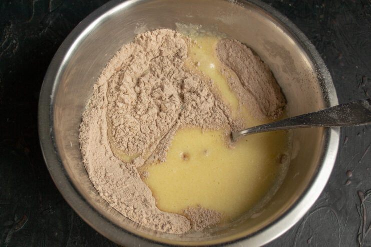 Combining wet and dry ingredients for the cake batter. The process of mixing wet and dry ingredients to form the cake batter.