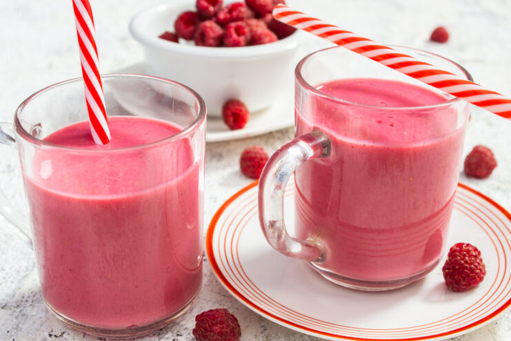 A glass of refreshing kefir and raspberry smoothie, garnished with fresh raspberries.