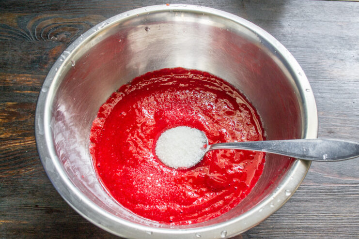 Step 3: Sweetening the raspberry puree to your taste. Adding sugar to the bowl of seedless raspberry puree.