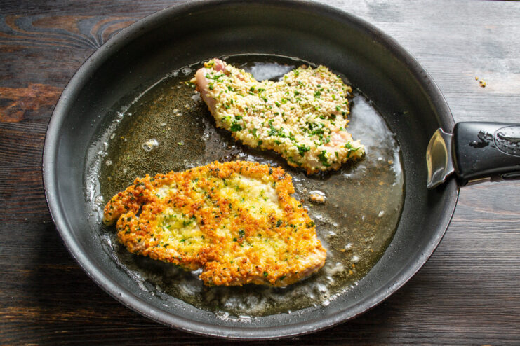Frying Pork Chops to a Perfect Golden-Brown Two breaded pork chops sizzling in hot oil in a non-stick frying pan.