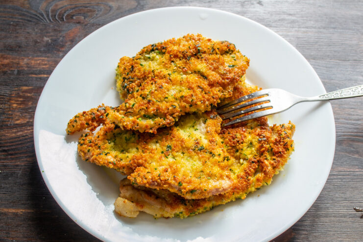 Draining Excess Oil from Fried Pork Chops for a Crispy Finish Golden-fried pork chops resting on a paper towel to absorb excess oil.