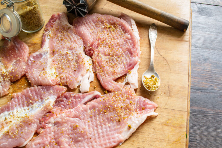 Seasoning Tenderized Pork with Aromatic Svanskaya Sol Hand sprinkling Svanskaya sol, a Georgian spice blend, over thin pork cutlets.