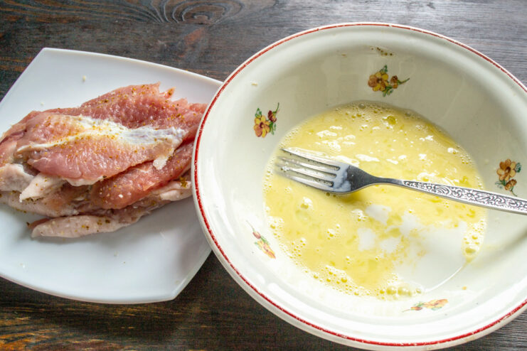 Preparing the Egg Wash for Breading Pork Chops A raw egg and milk in a white bowl, being prepared for the egg wash.