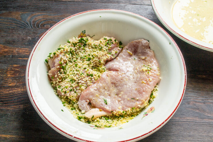How to Perfectly Bread Pork Chops without a Mess A pork chop coated in egg wash being covered with seasoned panko breadcrumbs.