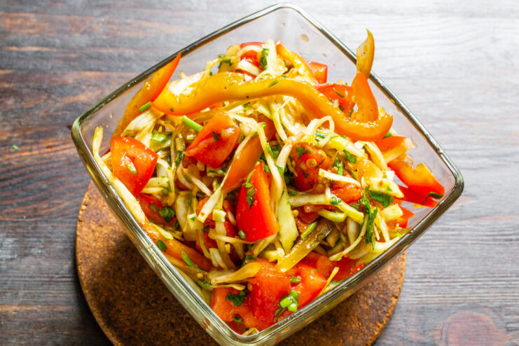 A close-up shot of the finished vegetable salad with honey dressing in a white bowl.