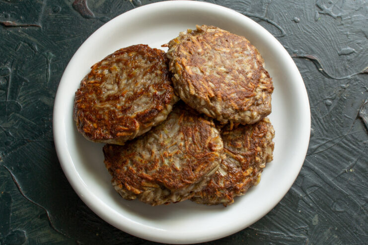 Placing cooked patties on paper towels to absorb excess oil for a healthier result. Golden-brown cooked vegetable patties resting on a paper towel to drain excess oil.
