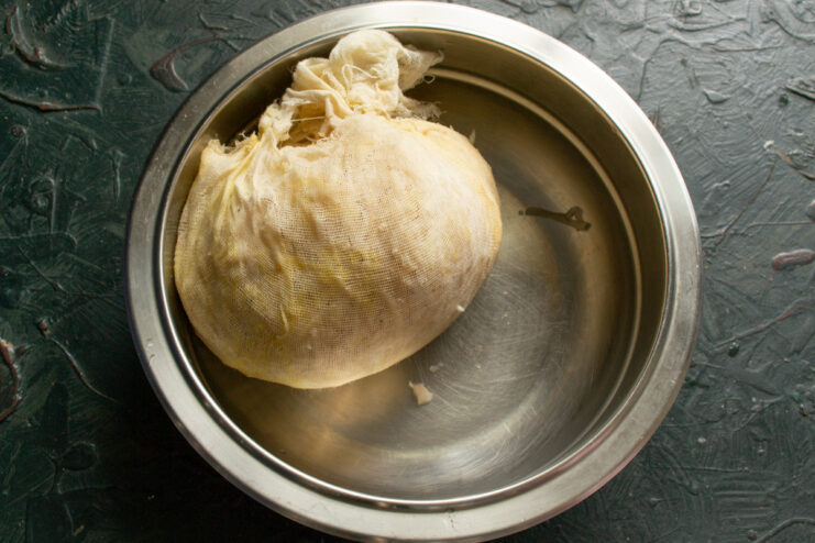An important step: squeezing excess moisture from the grated vegetables to ensure crispy patties. Squeezing grated vegetables wrapped in cheesecloth to remove excess water.