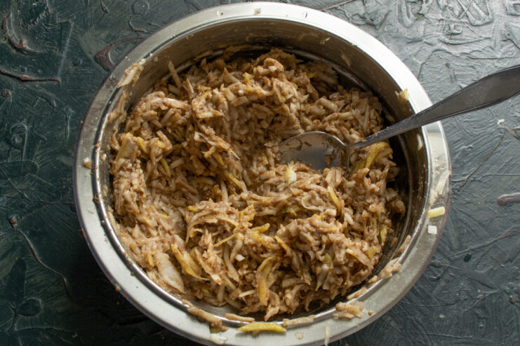 Combining all ingredients to form a thick, sticky batter for the Jerusalem artichoke patties. A close-up of the thoroughly mixed vegetable patty batter in a bowl.