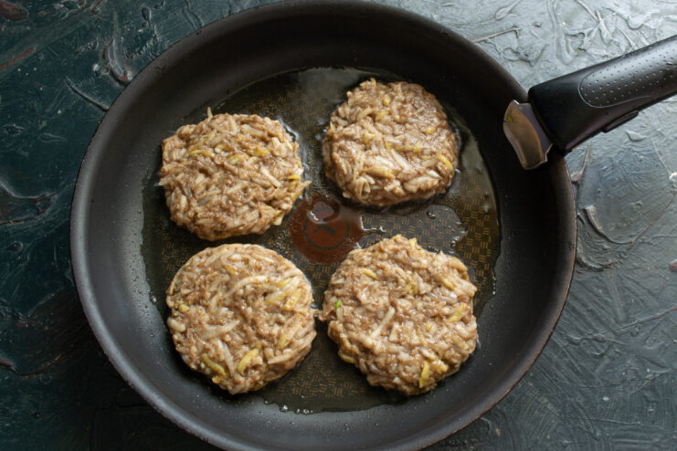 How to form the patties: use wet hands to prevent the mixture from sticking. A hand forming a round vegetable patty from the Jerusalem artichoke mixture.