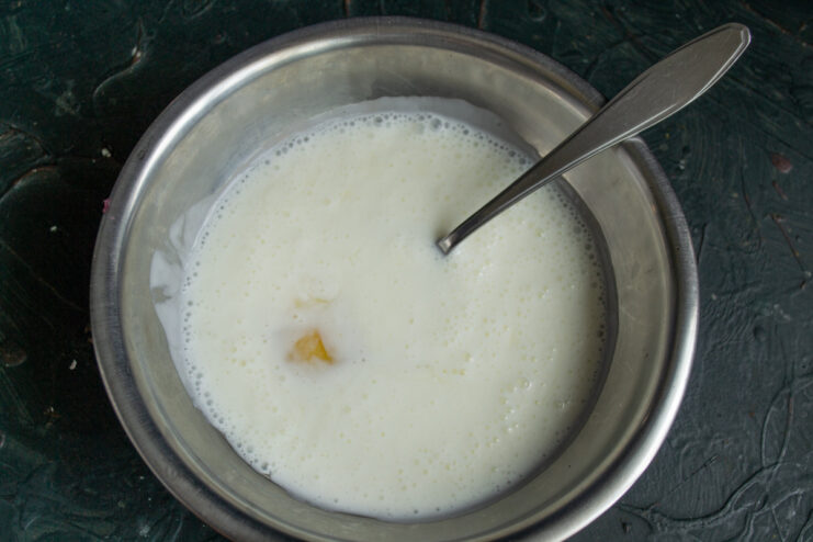 Step 1: Combining Egg and Kefir for the Batter A glass bowl containing a cracked egg and kefir, ready to be mixed.