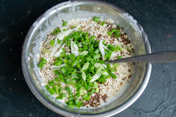 Preparing the Fresh Herbs: Chopping Green Onions A bunch of fresh green onions being finely chopped on a cutting board.