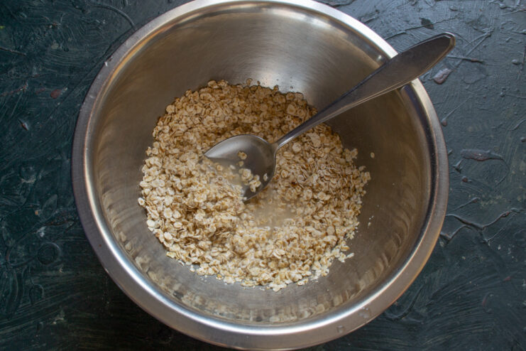 Preparing the base for the Ovsyanoblin batter A glass bowl filled with quick-cooking rolled oats, ready for making the pancake batter.