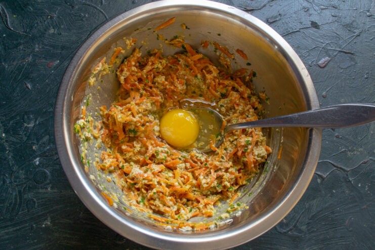 Adding eggs to bind the oatmeal pancake batter Two raw chicken eggs cracked into the bowl with the carrot and oatmeal batter.
