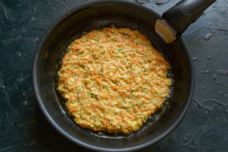 Cooking the Ovsyanoblin in a non-stick pan Spooning the carrot and oatmeal batter onto a hot, oiled non-stick pan to form a pancake.
