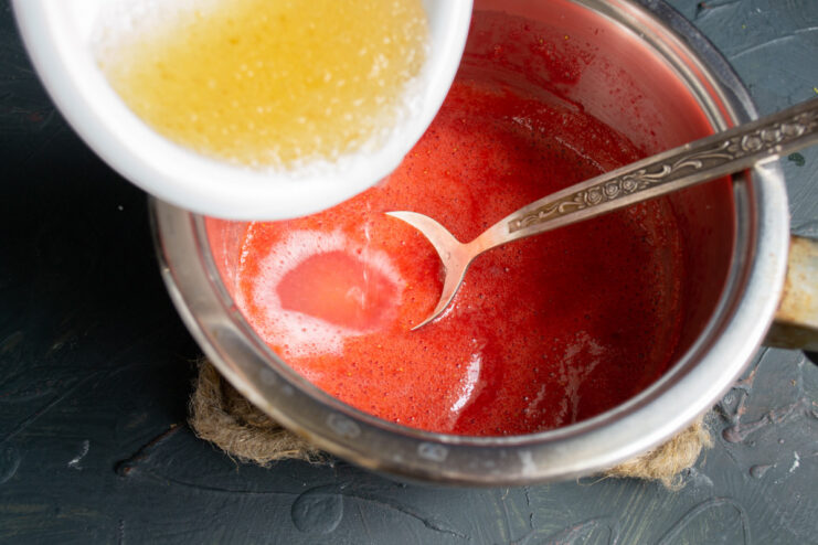 Step 6: Heating the Strawberry Puree A saucepan on a stove with bright red strawberry puree being heated.