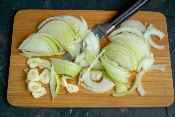 Step 1: Preparing the Onions for the Pâté A hand slicing a yellow onion into thin half-rings on a cutting board.
