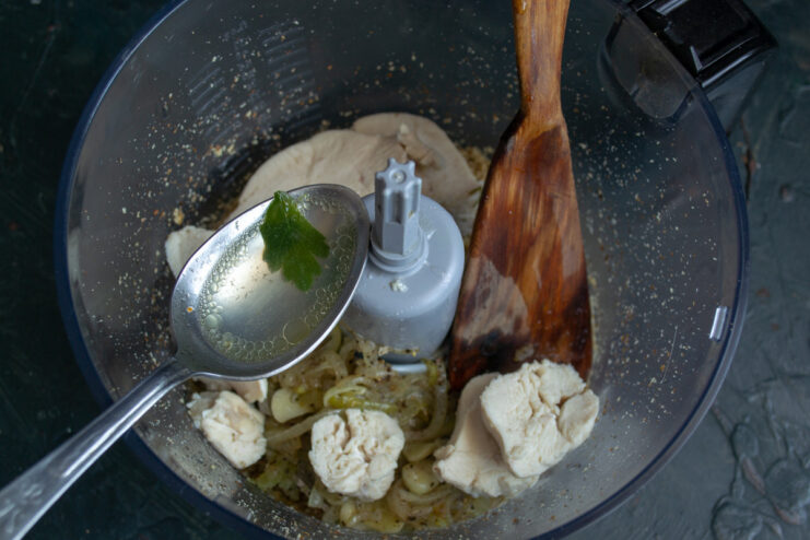 Adding Chicken and Broth for a Creamy Pâté Chopped chicken breast and chicken broth being added to the blender with walnuts and onions.