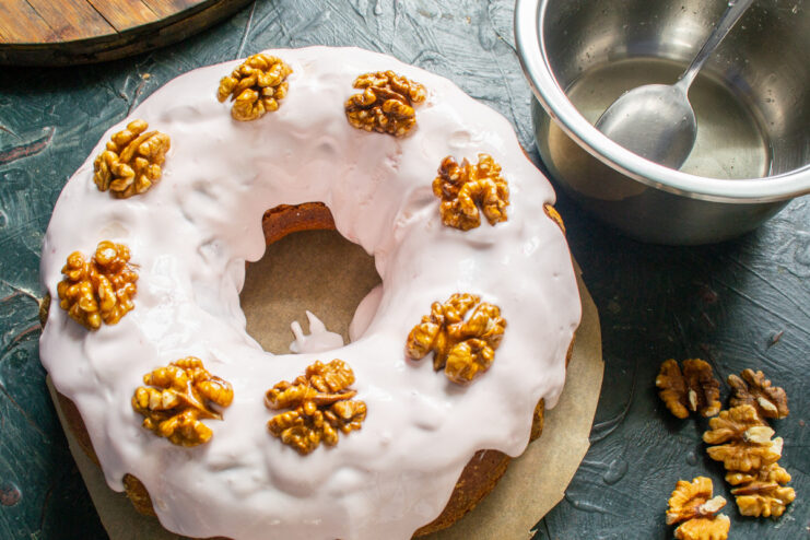 Adding the Final Touch: Honey-Glazed Walnuts Placing honey-glazed walnut halves on top of the pink frosting on the pie.