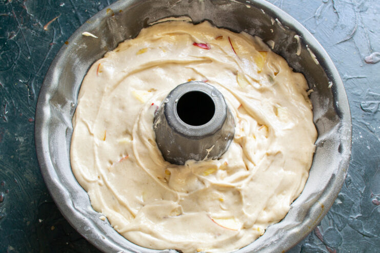 Preparing the Pie for Baking in a Bundt Pan Pie batter being spread evenly in a greased and floured Bundt pan with a spatula.