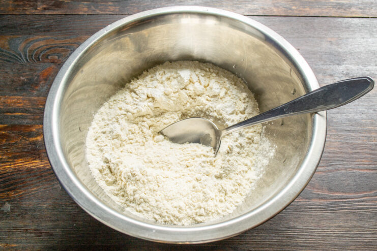 Sifting Flour: The First Step to a Perfect Pastry A hand sifting all-purpose flour into a large glass bowl for the pie dough.