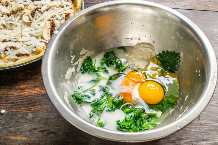 Making the Creamy Nettle Custard Filling A bowl containing blanched and squeezed nettles, eggs, and milk for the pie filling.