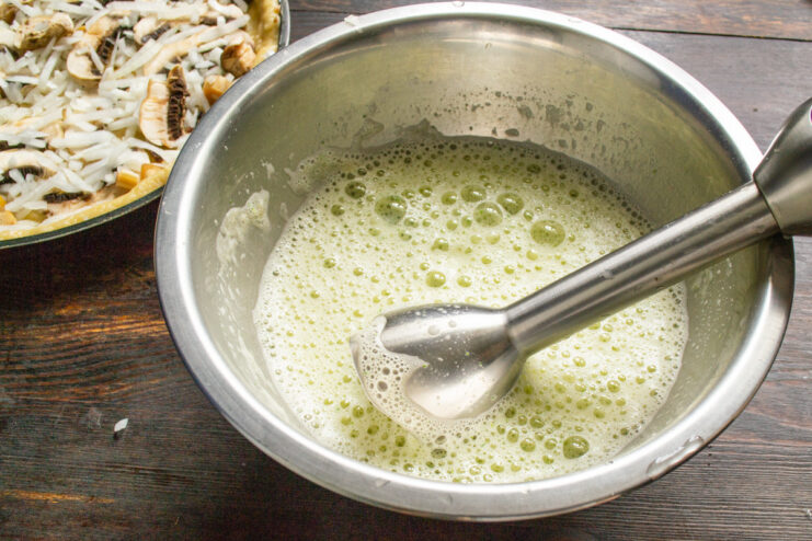 Blending the Filling Until Smooth An immersion blender mixing the nettle and egg mixture into a smooth, green liquid.