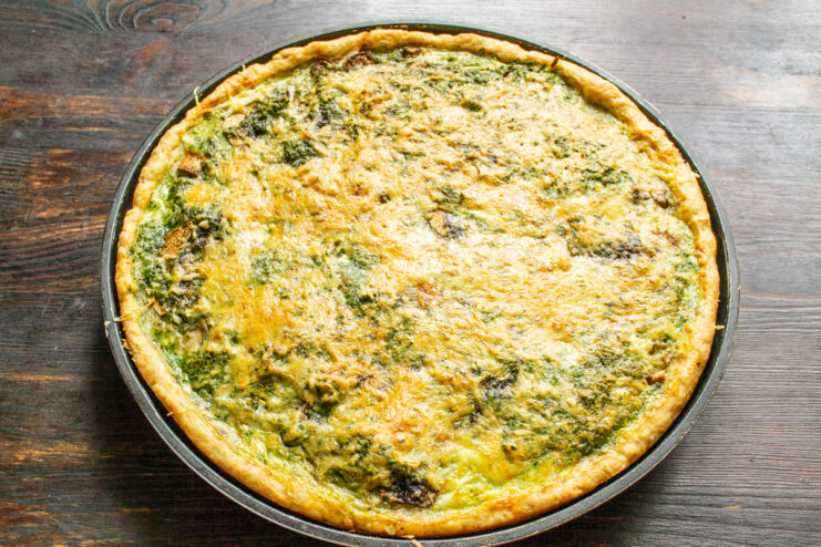 Baking the Pie to a Perfect Golden Brown The fully assembled nettle and mushroom pie in its pan, baked to a perfect golden brown.