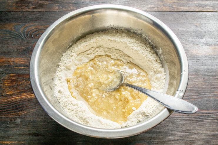 Combining Wet Ingredients for the Pie Dough Adding salted water to the bowl with flour and oil to form the pie dough.