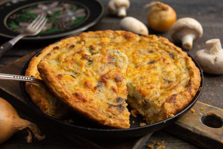 A whole baked mushroom and cheese pie with a golden-brown crust, ready to be served.