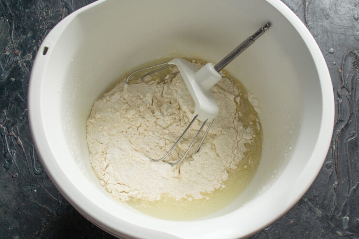 Step 2: Combining dry ingredients for the pie crust Flour and baking powder being added to the wet ingredients in a food processor.