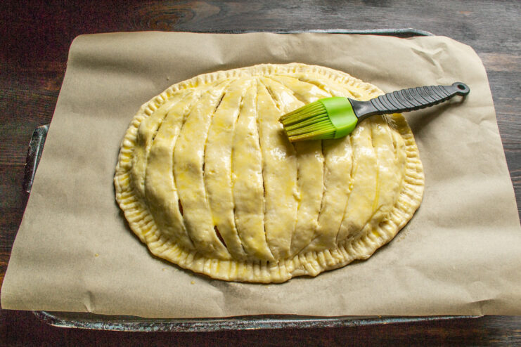 Applying Egg Wash for a Golden Crust Brushing the assembled pumpkin-shaped pie with egg wash before baking.