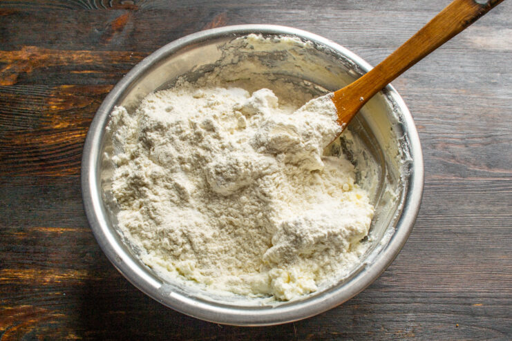Mixing the Dough into a Crumbly Texture Hands rubbing flour into a butter and cheese mixture to create a crumbly dough.