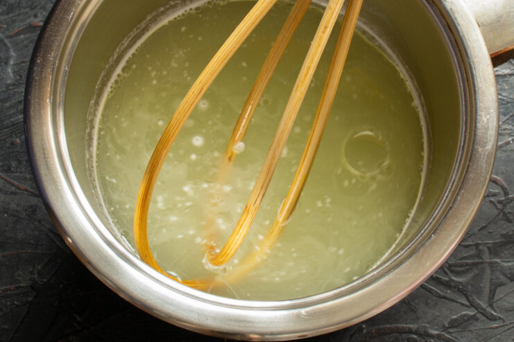 Preparing the Pirozhki Dough: Boiling Whey and Oil Heating whey and vegetable oil in a saucepan on the stove.