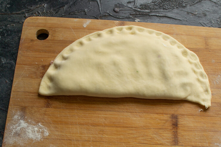 Folding and Sealing the Pirozhki Folding the dough over the filling to create a half-moon shaped pirozhok.