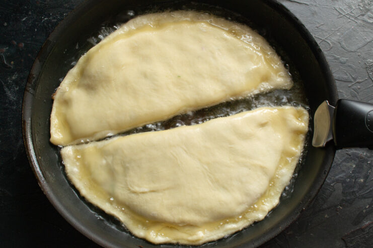 Frying the Pirozhki to Golden Perfection Pirozhki frying in hot oil in a skillet until golden brown.