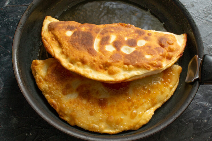 Ensuring an Evenly Cooked, Crispy Pirozhok Flipping a pirozhok in a skillet to fry the other side.