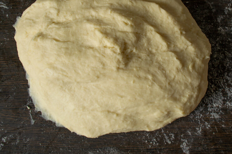 Kneading and Resting the Dough for Tender Pirozhki A ball of soft dough resting on a floured surface.