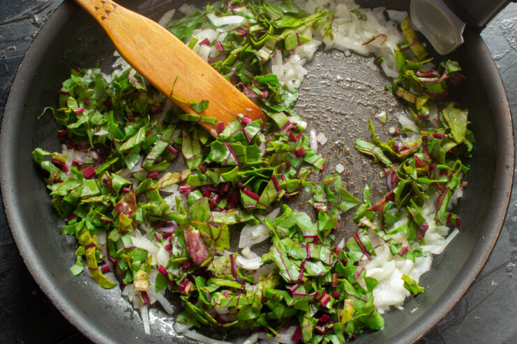 Chopping Vegetables for the Pirozhki Filling Chopped onions and beet greens on a cutting board.