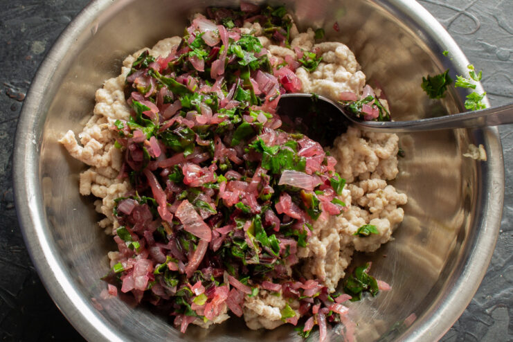 Combining Ingredients for the Savory Filling Sautéed vegetables being mixed with ground meat in a bowl.