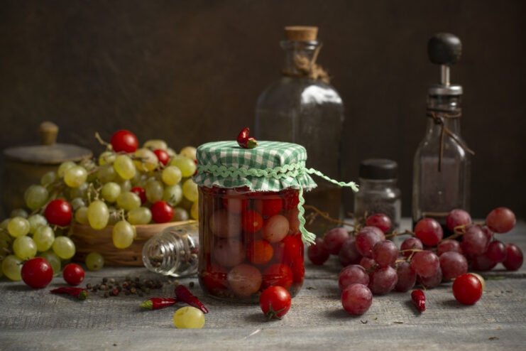 A sealed glass jar of pickled cherry tomatoes and grapes, ready for winter storage.