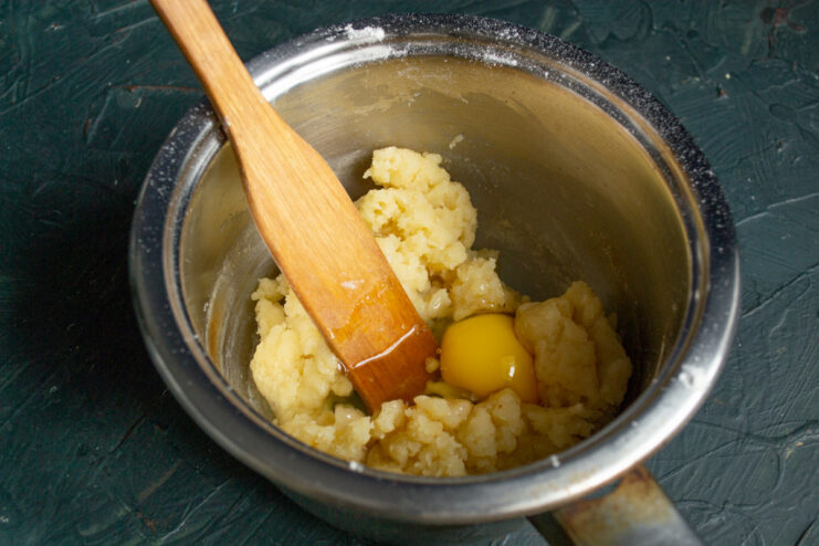 Adding Flour to Create the Choux Pastry Base Adding a mound of all-purpose flour into the boiling milk and butter mixture in a saucepan.