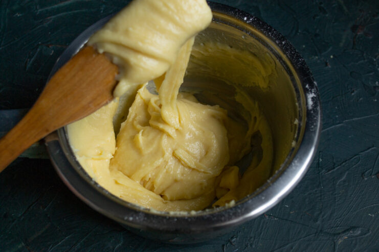 Checking for the Perfect Choux Pastry Consistency A spatula lifting choux pastry dough, showing it falling in a thick V-shape or ribbon.