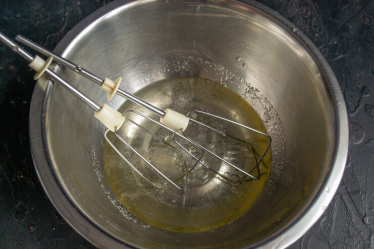 Whisking Oil, Water, and Salt to Create an Emulsion for the Dough A glass bowl with oil, water, and salt being whisked into an emulsion.